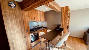 A compact kitchen with wooden cabinetry, a central island with chairs, and a built-in oven.