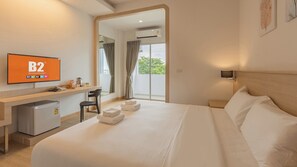 Ein Hotelzimmer mit Bett, Schreibtisch, Stuhl, Fernseher und Blick ins Freie.