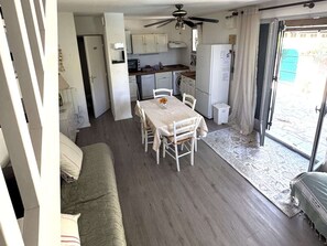 A compact living space with a dining area, kitchenette, and a sofa. - Semi-detached T3 villa with pool and parking (Cap d'Agde)
