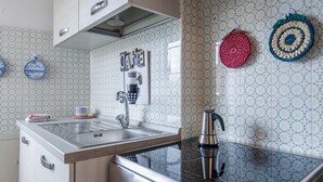 A modern kitchen with a stainless steel sink, a coffee machine, and decorative wall tiles.