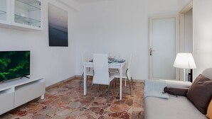 A living room with a dining area, a television, a door, and a lamp.