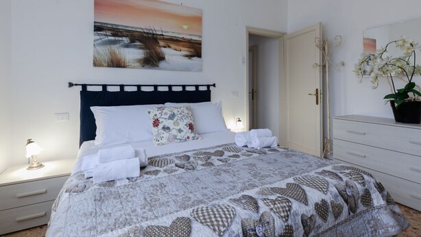 A bedroom with a bed, a nightstand, a dresser, and a painting on the wall.