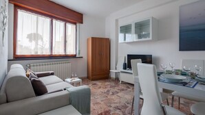 A modern living room with a sofa, dining table, and a TV.