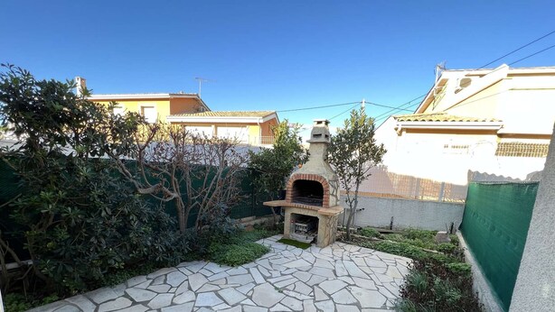 A stone patio with a brick oven, surrounded by greenery and residential buildings. - 2-Room Pavilion with Parking, Near Beach, 6 People (Valras-Plage)