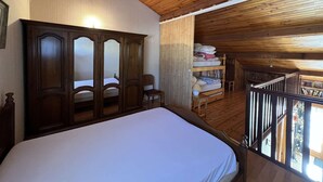 A wooden-paneled room with a bed, a wardrobe, and a small seating area. - 2-Room Pavilion with Parking, Near Beach, 6 People (Valras-Plage)