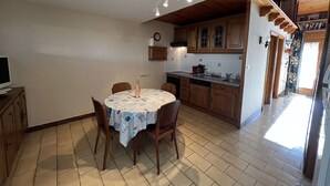 A kitchen with wooden cabinets, a dining table with chairs, and a tiled floor. - 2-Room Pavilion with Parking, Near Beach, 6 People (Valras-Plage)