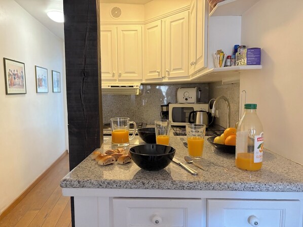 A kitchen with white cabinets, a coffee maker, a toaster, and a bottle of orange juice.