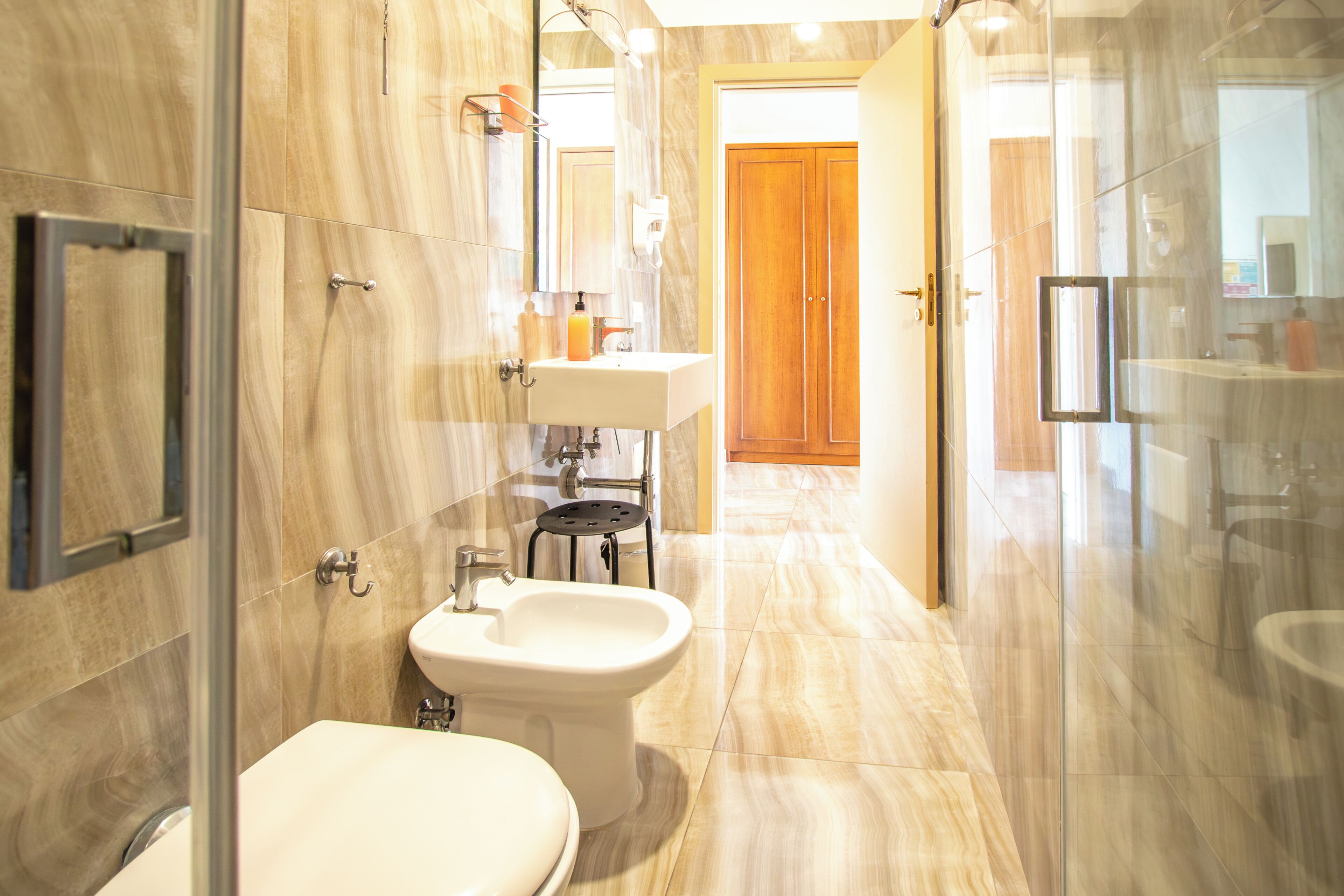 A modern bathroom with a bidet, toilet, and glass shower enclosure.