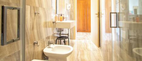 A modern bathroom with a bidet, toilet, and glass shower enclosure.