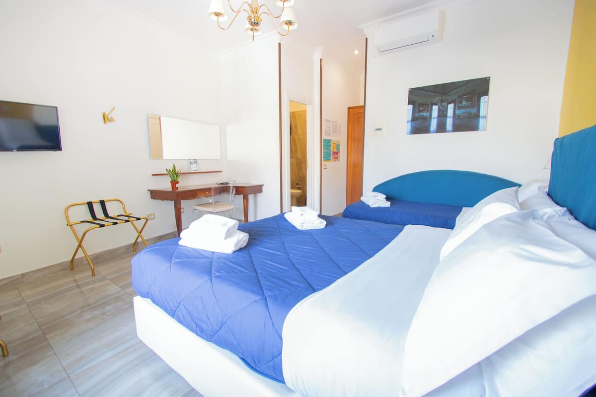 Hotellihuone, jossa on suuri sänky, työpöytä, tuoli, televisio ja peili.
