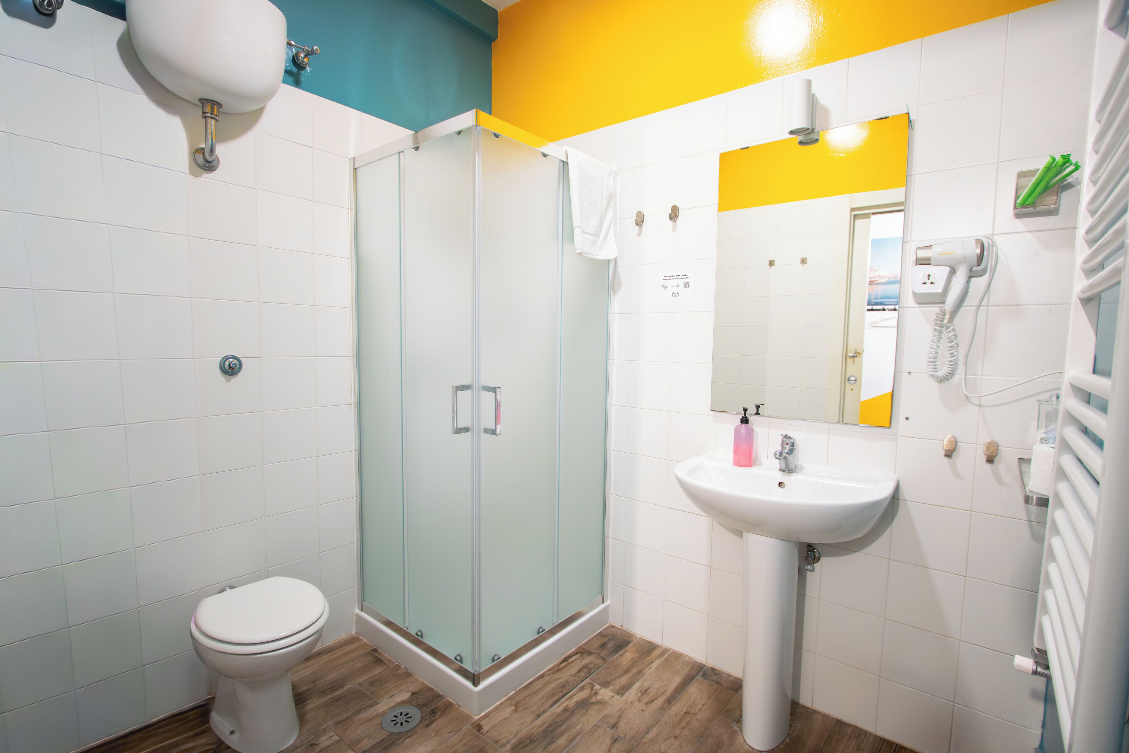 Un bagno con il water, una cabina doccia in vetro, un lavandino e uno specchio.