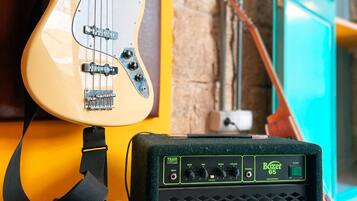 A guitar and amplifier in a room with a stone wall and a window.