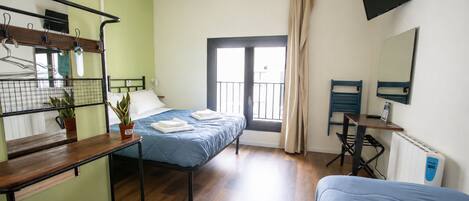 Quarto com cama, escrivaninha, cadeira, planta em vaso e janela com cortinas.