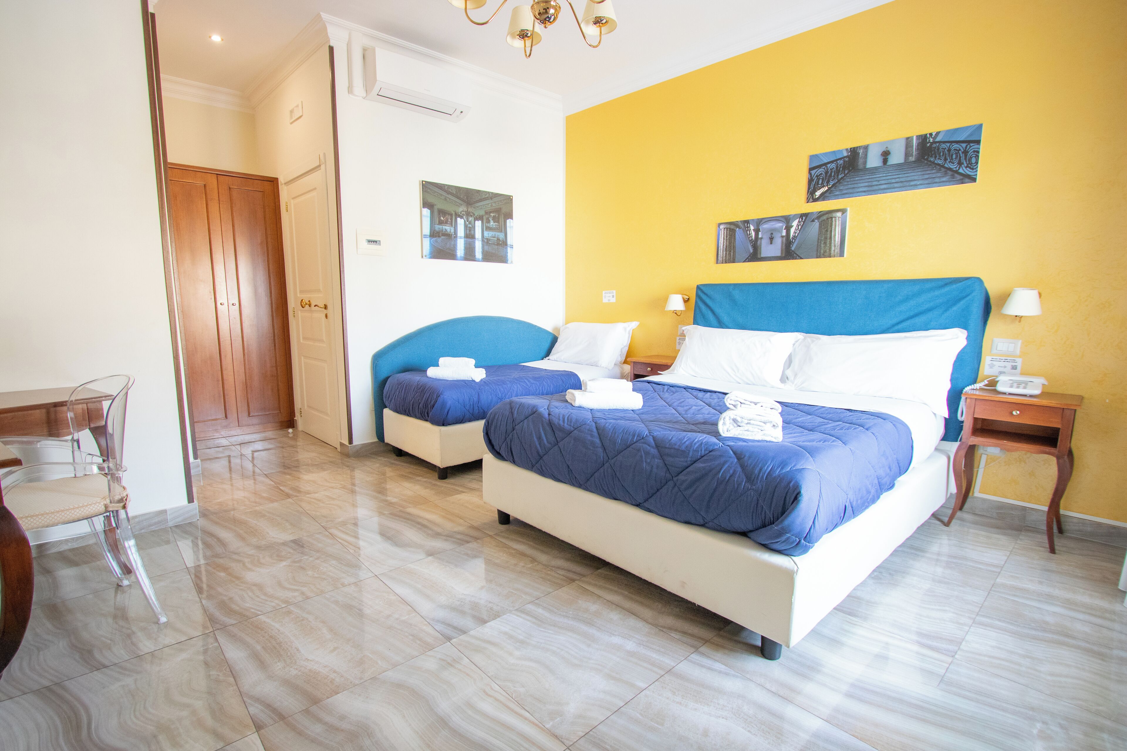 Una habitación de hotel con dos camas, una puerta de madera, una silla y una mesita.