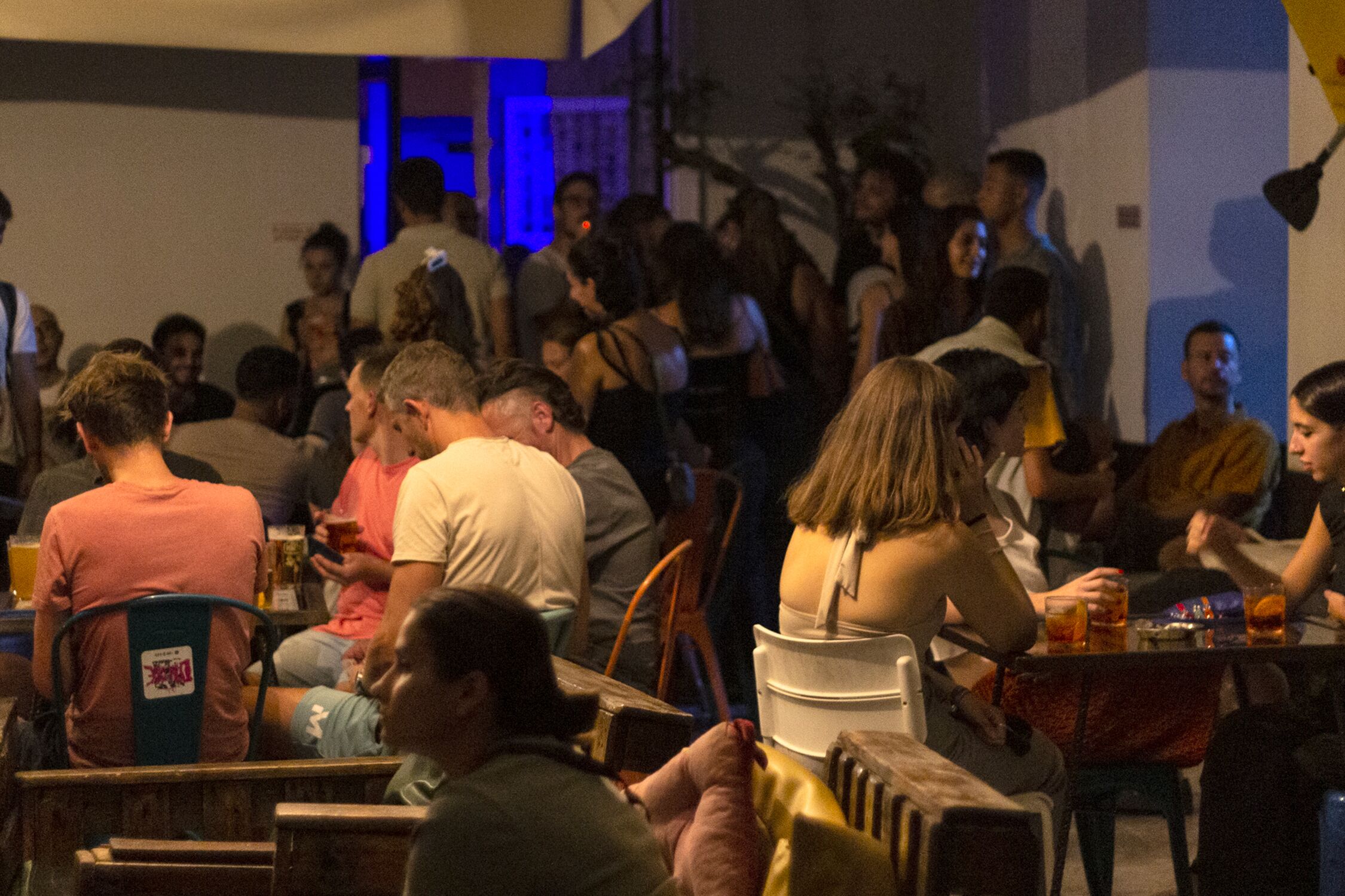 A crowded indoor space with people seated at tables, suggesting a social or dining venue.