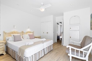 Una camera da letto con un letto grande, una sedia, un armadio e una ventola a soffitto.