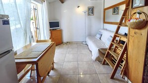A cozy room with a wooden table, a sofa, a TV on a cabinet, and a ladder against the wall.