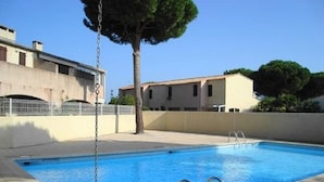 A rectangular swimming pool with a chain-link fence and metal pool ladder.