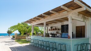 A seaside bar with outdoor seating and a menu board. - AFANDOU BAY SUITES HOTEL (Rhodes)