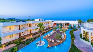 A modern hotel with a swimming pool, outdoor seating, and a view of the sea. - AFANDOU BAY SUITES HOTEL (Rhodes)