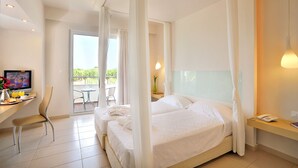 A hotel room with a bed, a desk with a chair, a TV, and a balcony with a table and chairs. - AFANDOU BAY SUITES HOTEL (Rhodes)