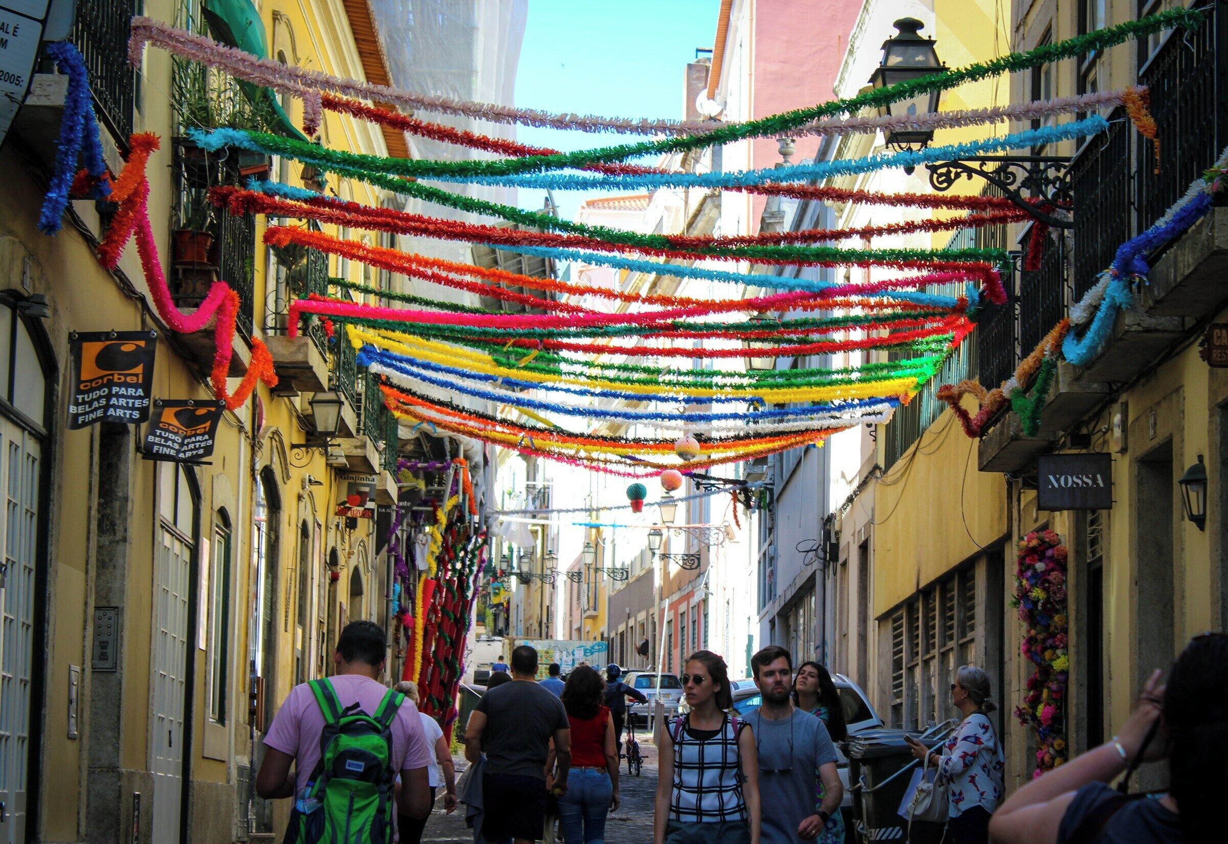 A narrow street with colorful decorations hanging overhead.