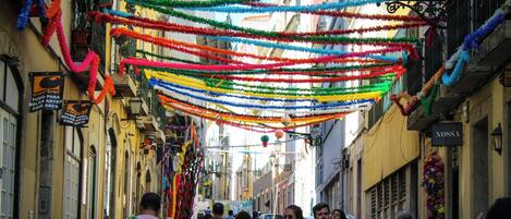 A narrow street with colorful decorations hanging overhead.