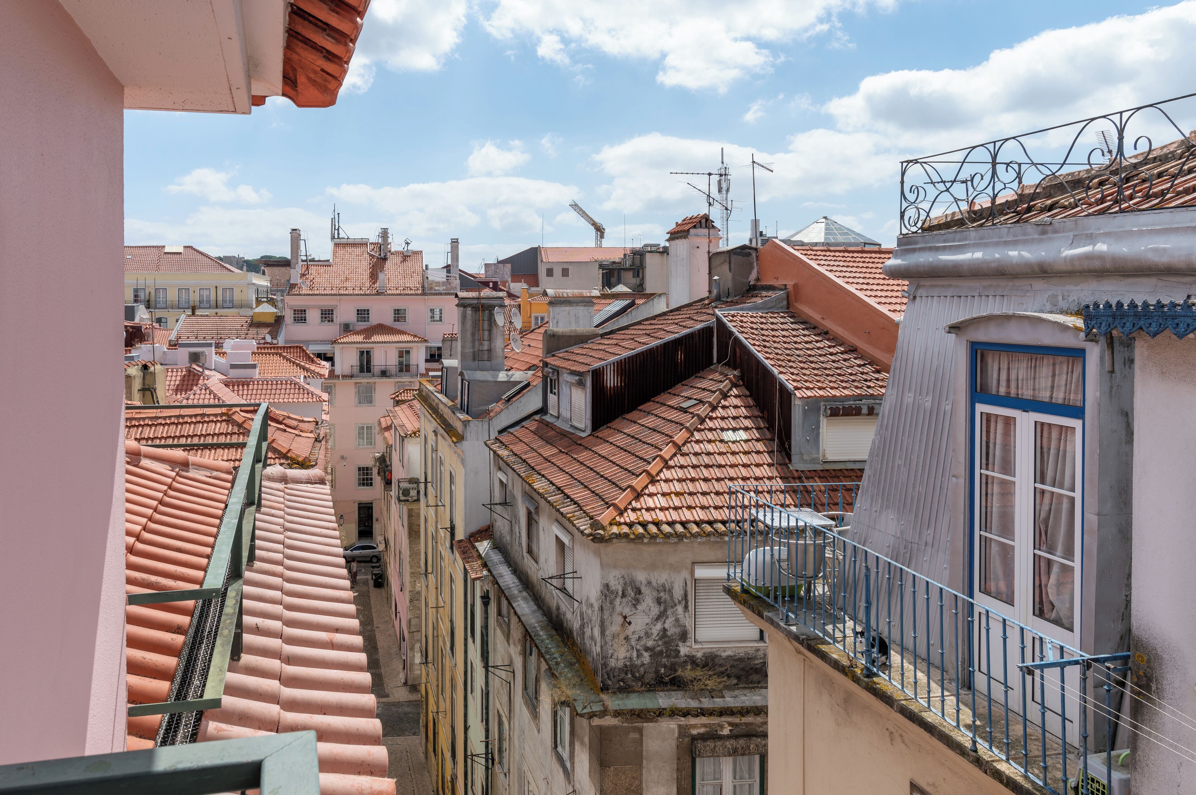 Una calle estrecha con edificios juntos, techos de tejas rojas y balcones.