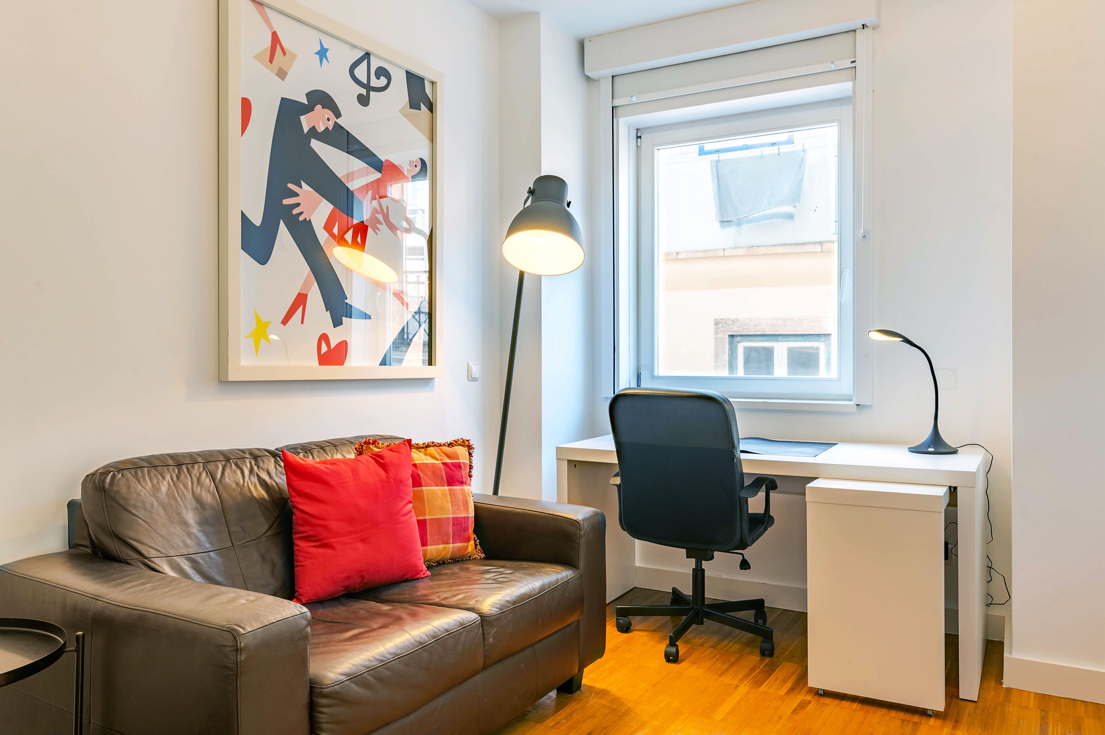 Una habitación moderna con un sofá de cuero, un escritorio y una lámpara de pie.