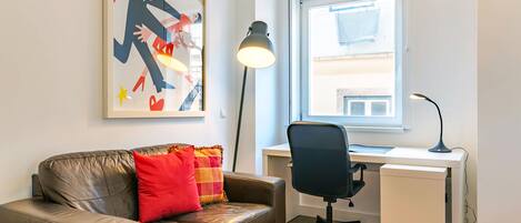 Una habitación moderna con un sofá de cuero, un escritorio y una lámpara de pie.