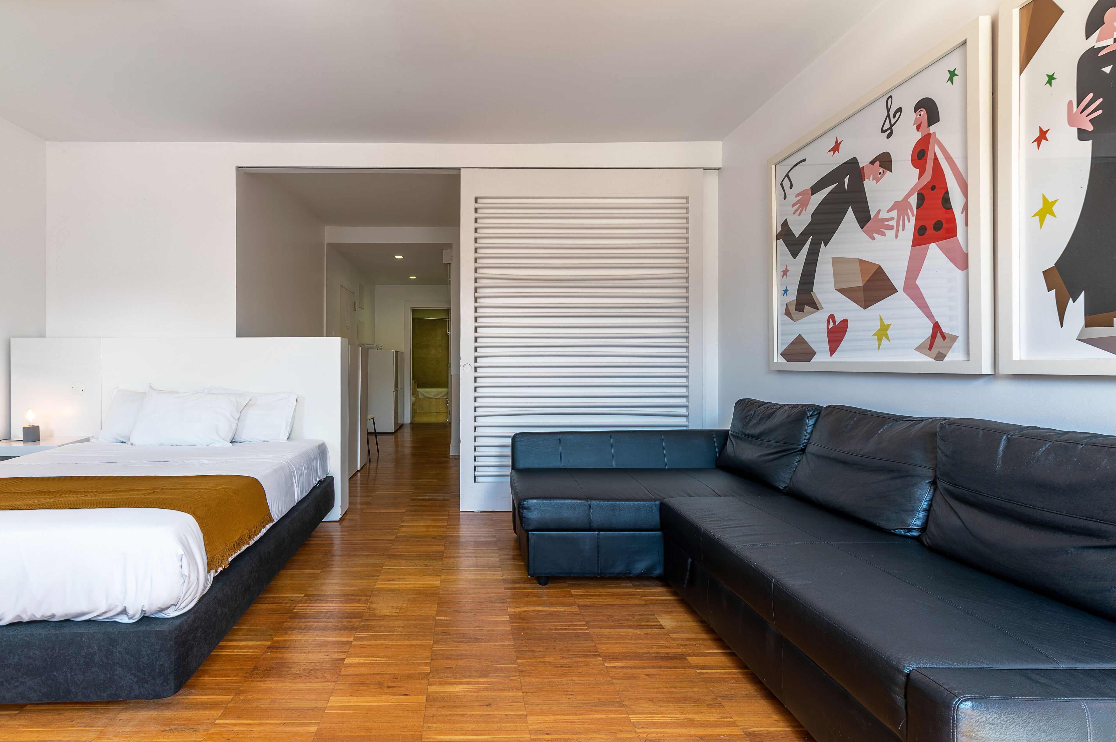 A modern hotel room with a bed, a sofa, and a large painting on the wall.