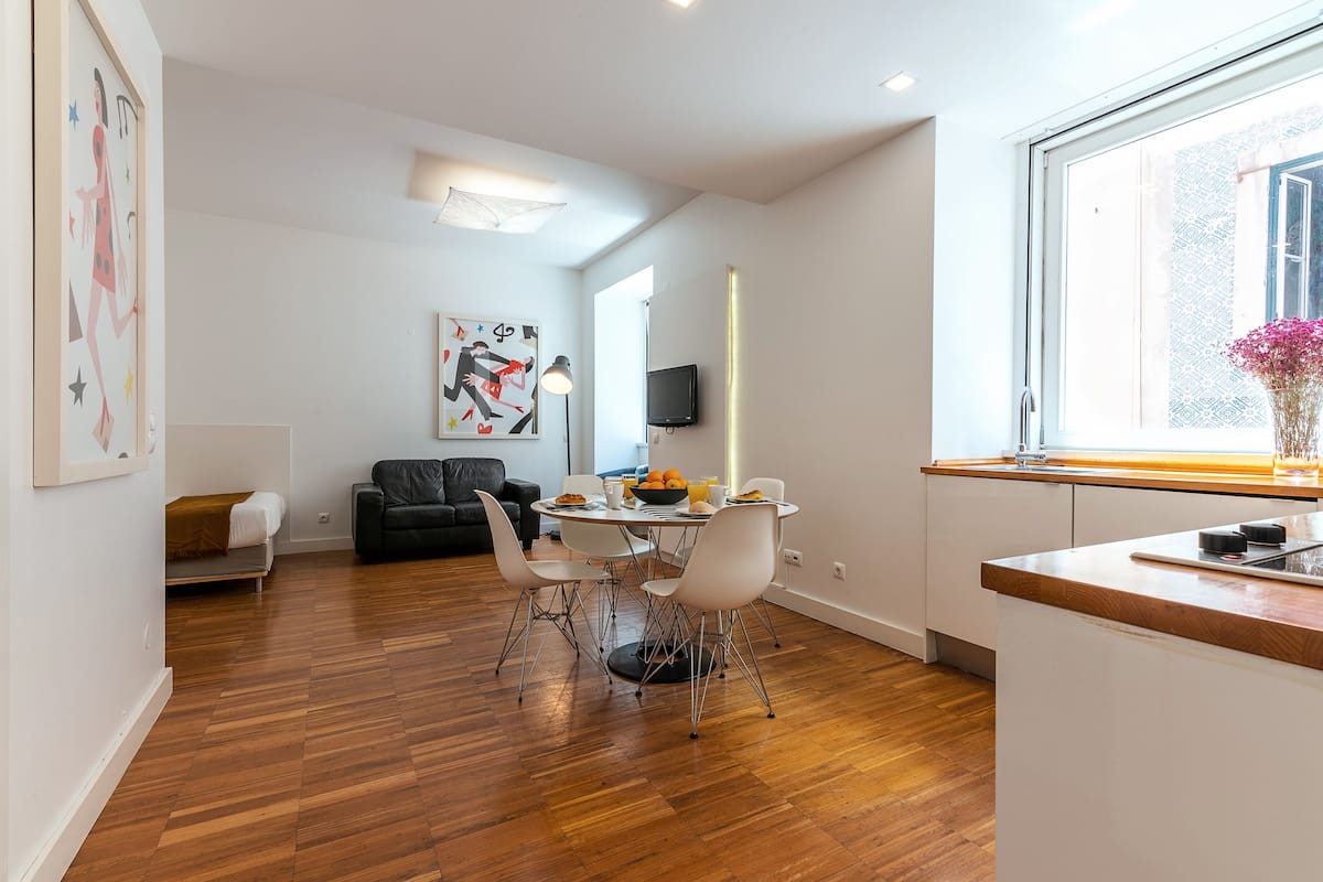 A modern living space with a dining area, a sofa, a flat-screen TV, and a window with a view.