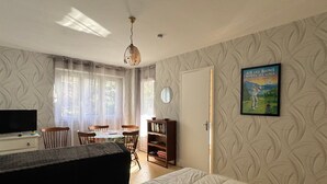 A bedroom with a bed, a TV, a desk with a chair, a bookshelf, and a poster on the wall. - 35m² Apartment with South-East Terrace and Private Parking (Aix-les-Bains)