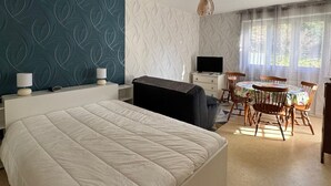 A bedroom with a bed, a desk, a chair, a television, and a dining table with chairs. - 35m² Apartment with South-East Terrace and Private Parking (Aix-les-Bains)