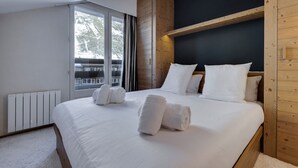 Une chambre d’hôtel moderne avec un grand lit, une tête de lit en bois et une vue sur un balcon.
