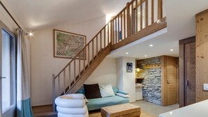 Un vaste espace de vie agrémenté d’un escalier en bois, d’un mur en pierre et d’un canapé bleu.
