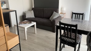 Een moderne woonkamer met een grijze bank, een witte salontafel en een eettafel met stoelen.