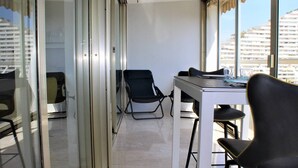 Een moderne kantoorruimte met een glazen scheidingswand, een witte tafel en zwarte stoelen.