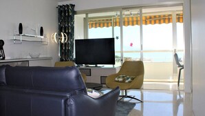 Een moderne woonkamer met een bank, een televisie en een balkon met uitzicht.