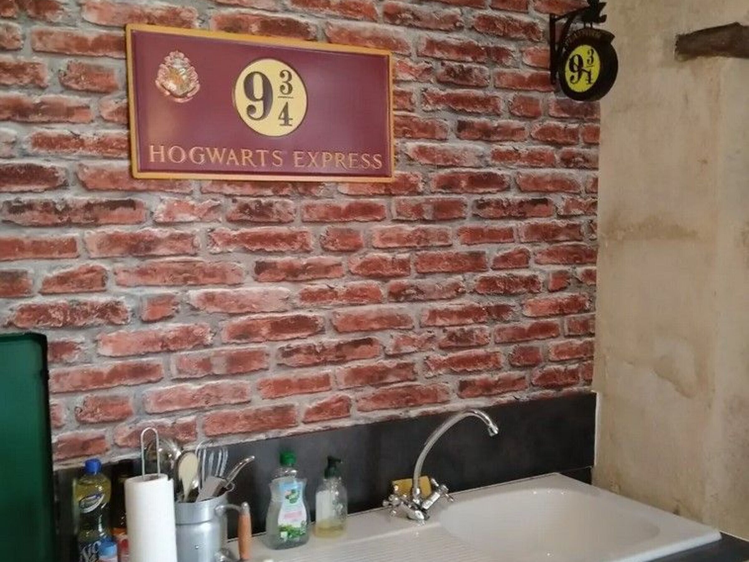 Un baño con pared de ladrillo, un lavamanos y un letrero que dice 'Hogwarts Express'.