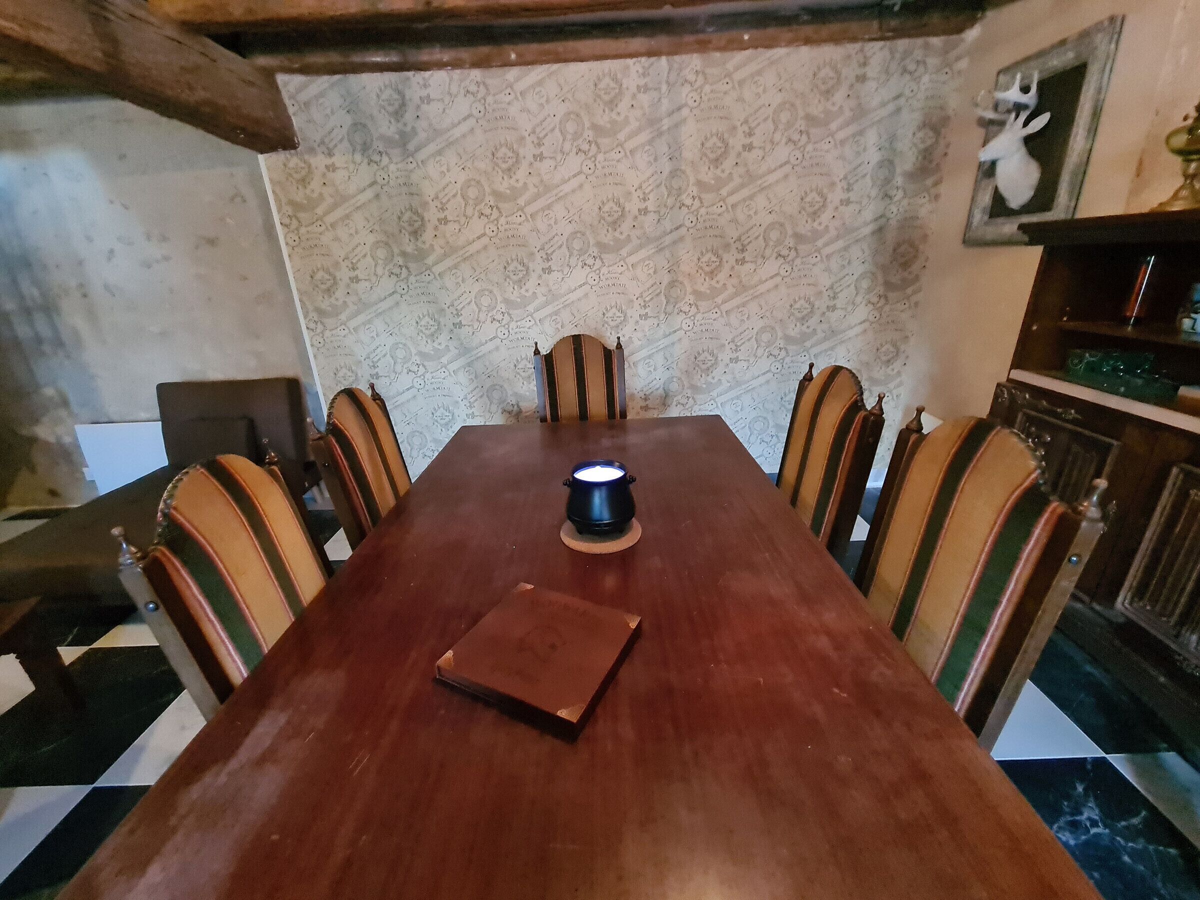 A wooden dining table with six chairs, a blue mug, and a brown book on it.