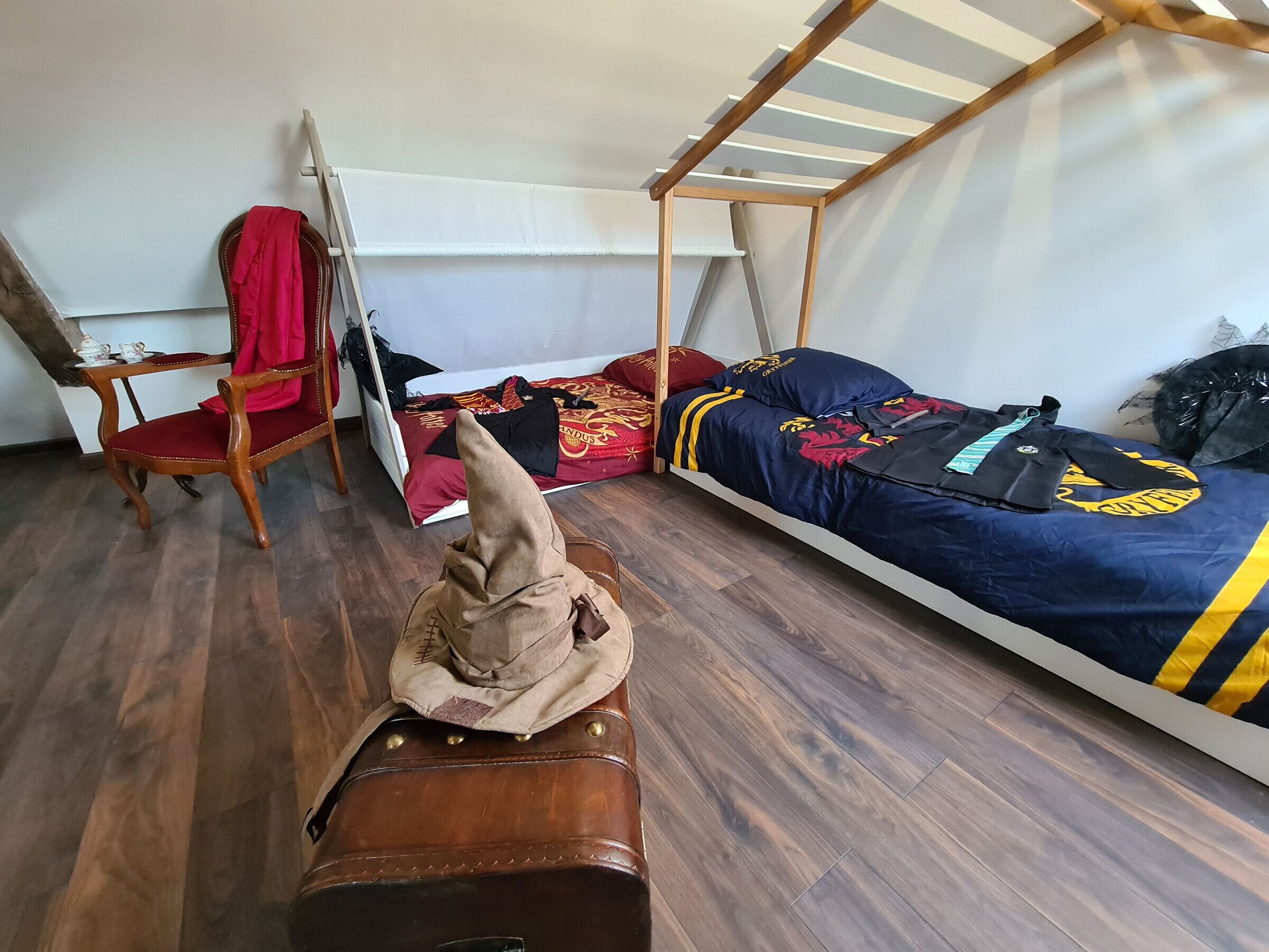 Une chambre à coucher avec un lit en bois, une chaise, une valise et une armoire.