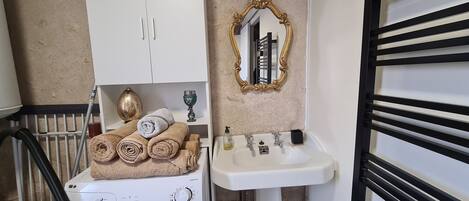 A compact laundry area with a washing machine, a cabinet, a sink, and a mirror.
