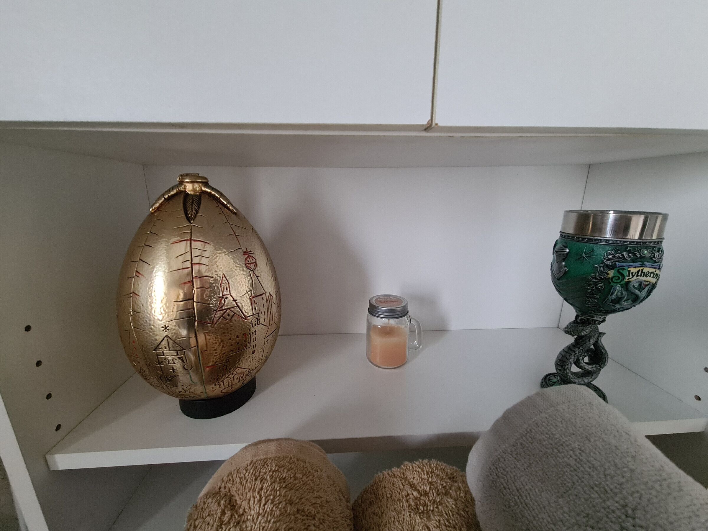 Una estant amb un globus decoratiu, una espelma i un vas verd.