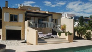 Et moderne hus med swimmingpool, overdækket terrasse og garage.