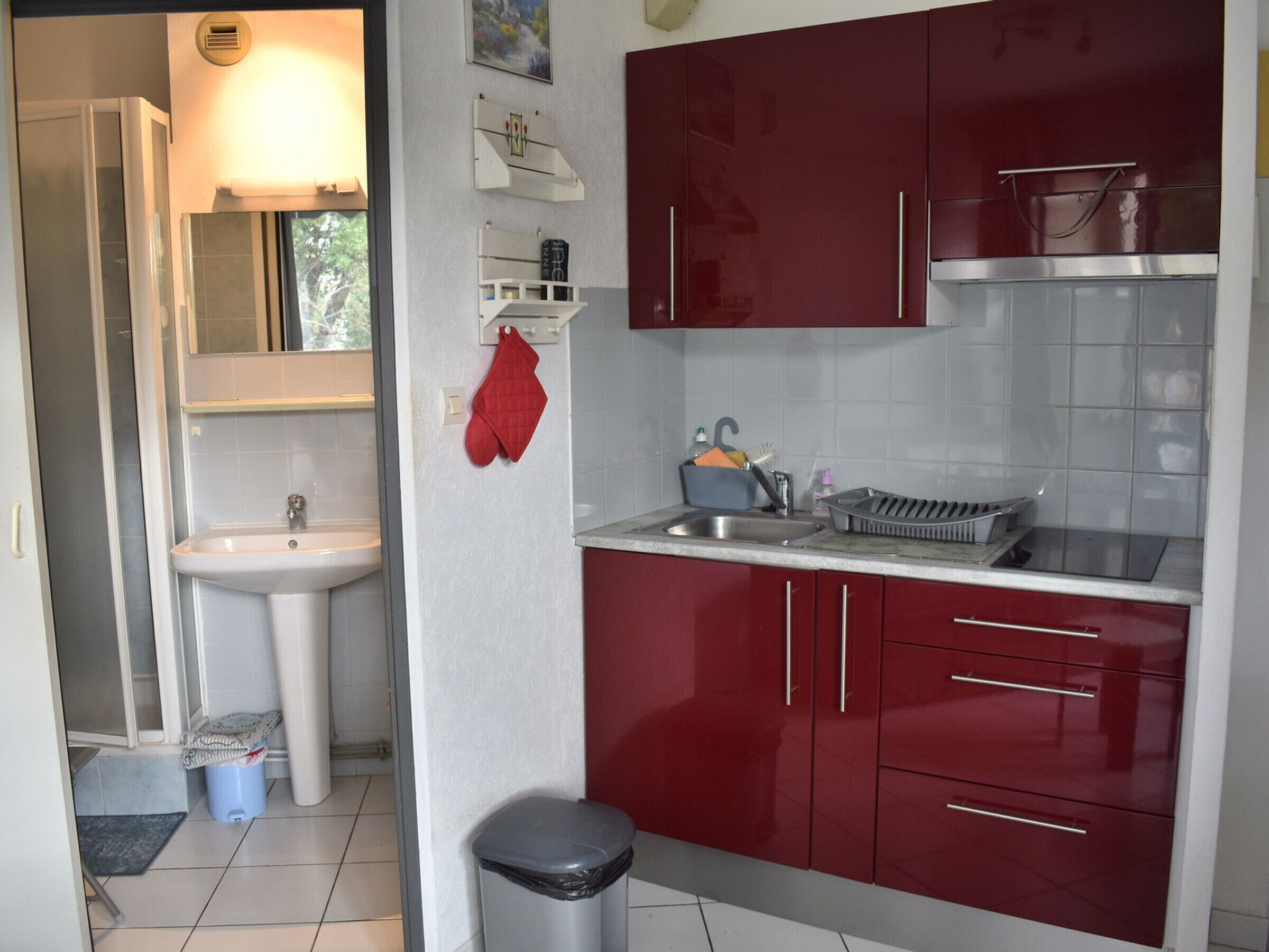 A compact kitchen with a sink, stove, and red cabinets.