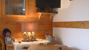 Een rustieke houten kamer met een houten tafel, een aan de muur bevestigde televisie en een teddybeer die een boek leest.