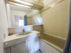 A bathroom with a white sink, mirror, and beige tiled walls.