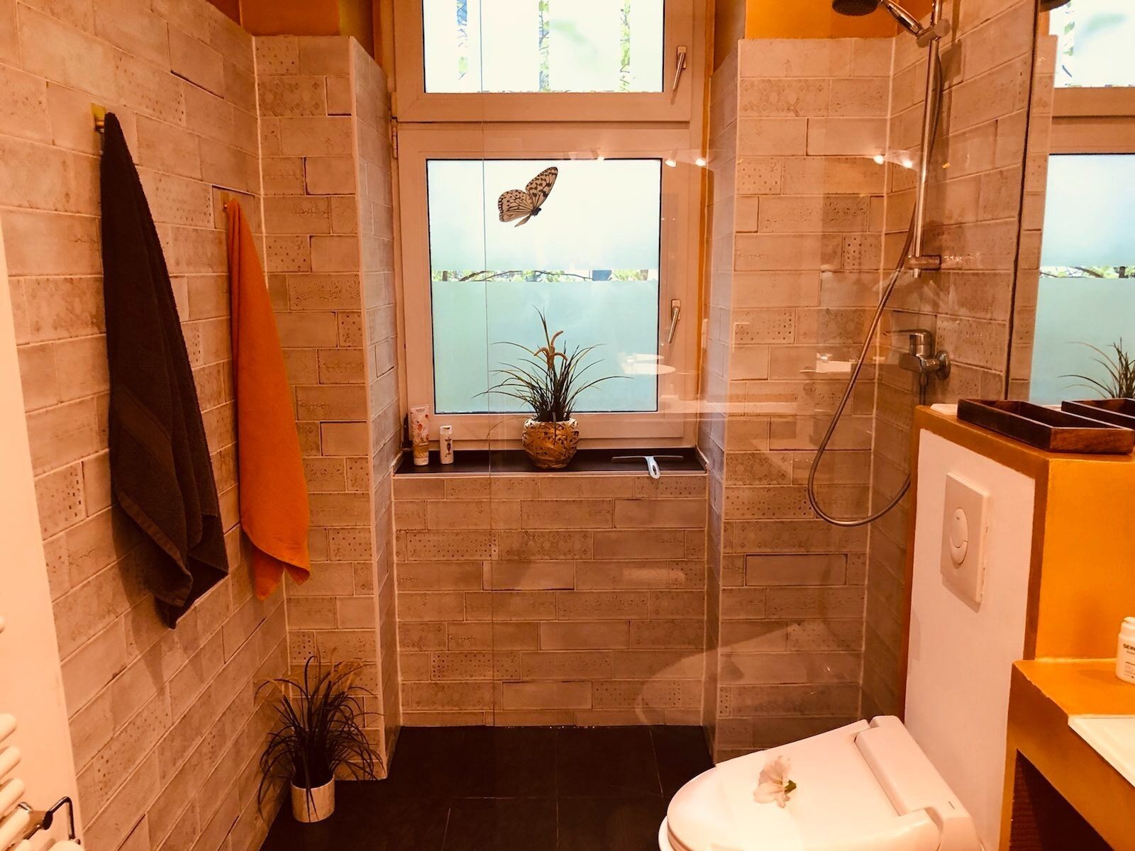 A bathroom with a window, a shower, and a toilet.