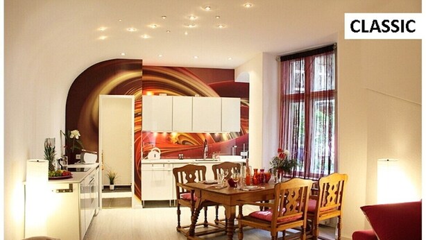 Un espace de vie compact comprenant un coin repas, une cuisine et un canapé rouge.